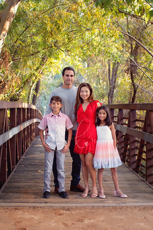family posed on bridge with fall trees