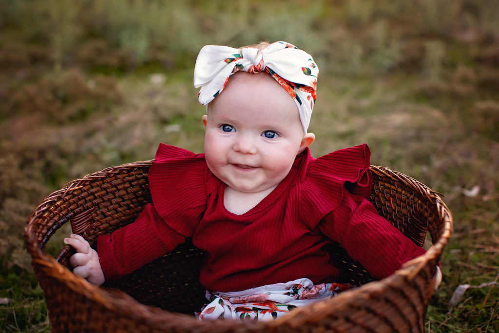 Photo of Baby Smiling in a basket for her Portrait Session in San Diego, CA with Kristin Rachelle 