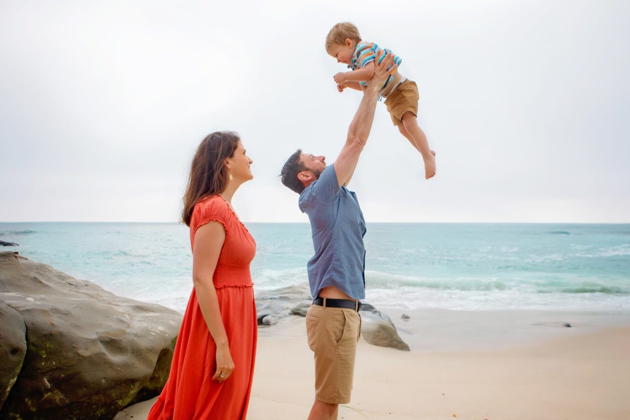 Candid Beach portrait of dad throwing baby in the air at La Jolla Beach
