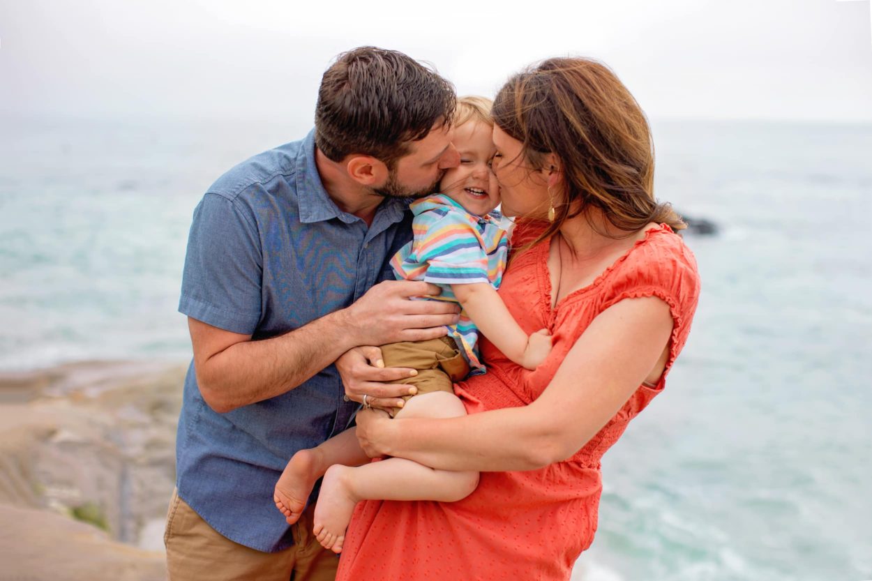 Mom and dad kissing baby for San Diego Family Beach Photographer 